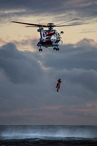 photo of person hanging on rescue helicopter during daytime thumbnail