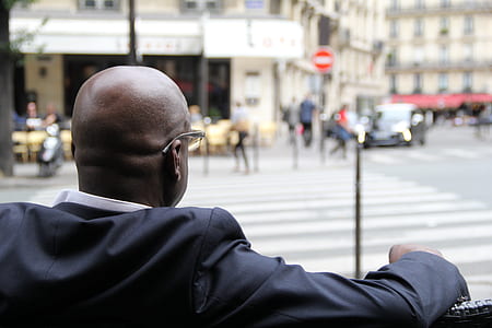 man wearing black suit on bench beside pedestrian crossing thumbnail