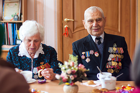 man sitting beside woman with white teacups beside and brown wooden behind thumbnail