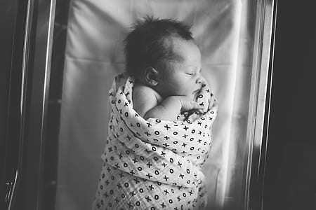 grayscale photography of baby in bed thumbnail