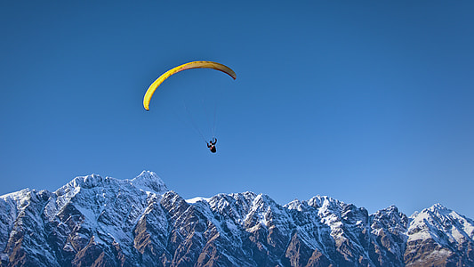 person wearing yellow paragliding with background of mountain thumbnail