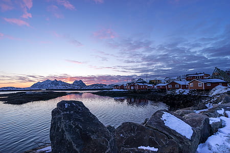 white and brown houses in front of body of water under cirrus clouds thumbnail