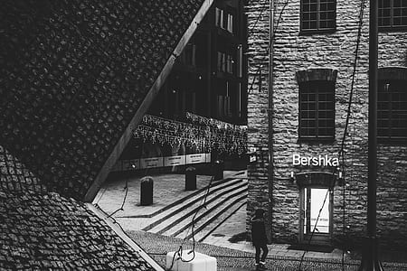 Person Standing Near Bershka Building Grayscale Photography thumbnail