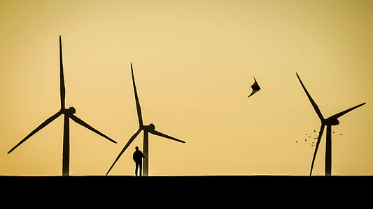 silhouette of person standing beside windmill thumbnail