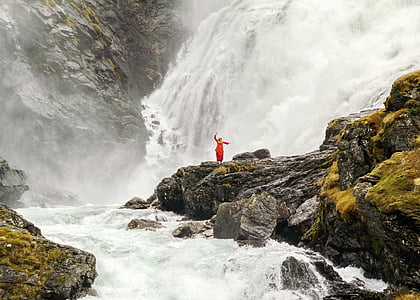 person standing on rock surrounded by waterfalls and river during daytime thumbnail