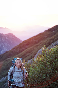 woman carrying backpack standing near leafed plant under blue sky during daytime thumbnail