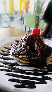 ice cream with chocolate syrup and cherry on top in white ceramic plate thumbnail