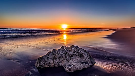 gray rock on sea shore during sunset thumbnail