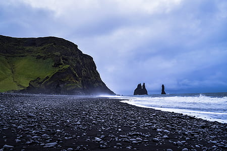 low angle photo of seashore near sea cliff during daytime thumbnail