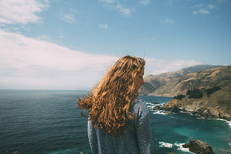 women's gray sweatshirt facing body of water and mountain view thumbnail