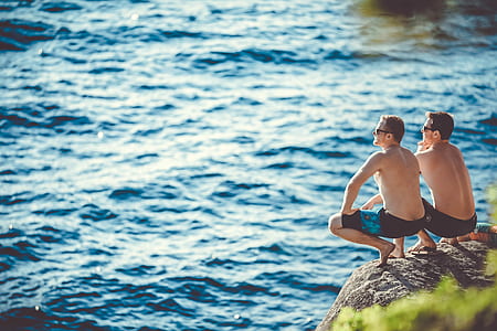 two men sitting on brown rock near cliff during daytime thumbnail