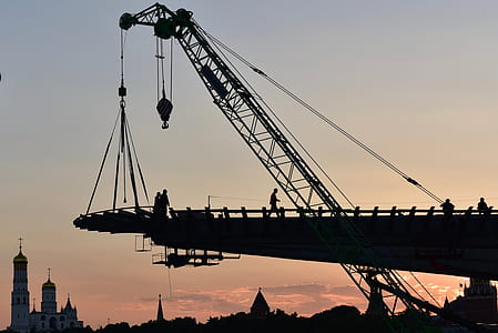 silhouette of person walking beside crane thumbnail