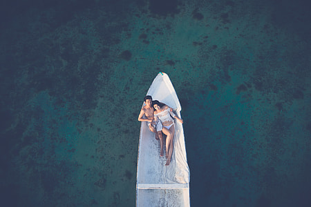 aerial photo of Couple riding white boat thumbnail