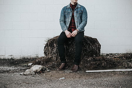 man wearing denim jacket sitting on rock thumbnail