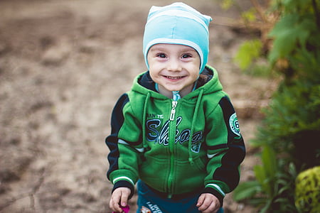 boy in green and black full-zip hoodie wearing blue and white knit cap thumbnail