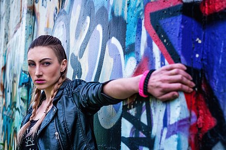 woman in black leather jacket standing in front of the wall thumbnail