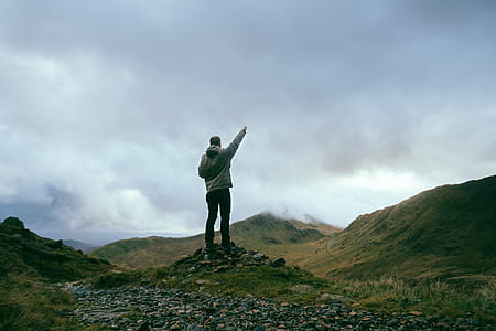 man raising his hand stepping on gray stones thumbnail