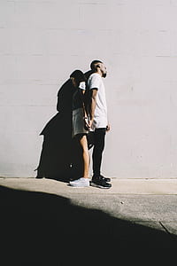 man and woman holding hands in front of gray wall thumbnail