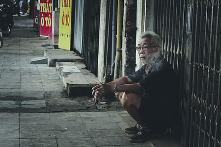 man sitting beside gray metal gate thumbnail