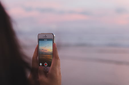selective focus photography of person holding turned-on iPhone 5s with seashore thumbnail
