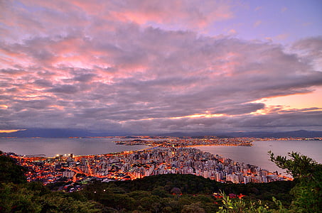 aerial photography of lighted city near body of water under cloudy sky during golden hour thumbnail