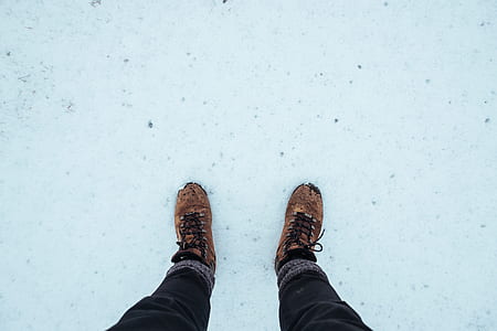 person wearing brown shoes step on ground covered by snow thumbnail