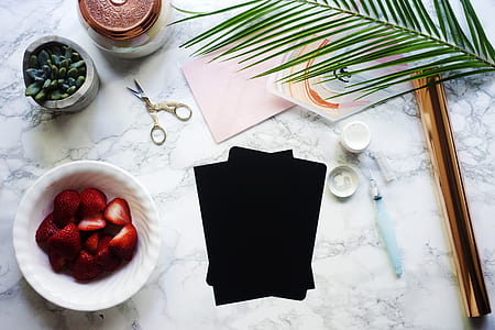 black and pink paper sheets with calligraphy pen and ink fountain beside bowl full of strawberry slices on white marble surface thumbnail