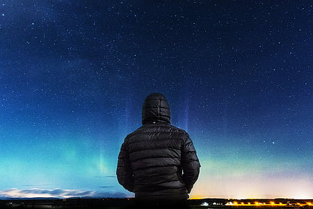 person wearing black bubble jacket while facing blue sky thumbnail