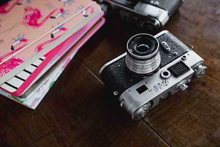 Old analog cameras and pink books on a wooden table thumbnail
