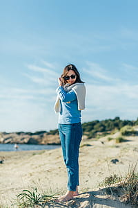 woman standing gray sand near body of water thumbnail