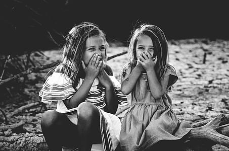 two girl's sitting on floor and holding there mouth while laughing thumbnail