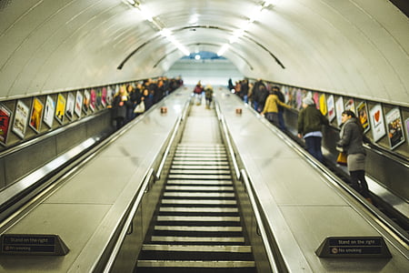 first person perspective photography of people riding escalator on tunnel thumbnail
