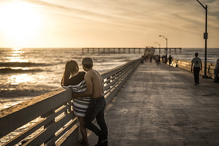 man cuddling woman beside rail thumbnail