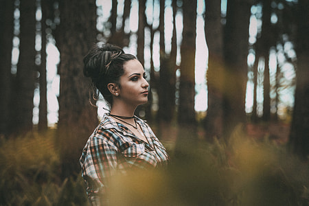 woman wearing black, teal, and brown plaid collared shirt in the woods at daytime thumbnail