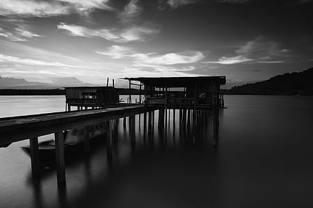 Greyscale Photo of Dock Near Mountains thumbnail