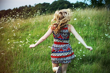 female in red dress on green grass field during daytime thumbnail