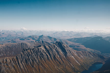 mountain range with body of water under cloudy skies thumbnail