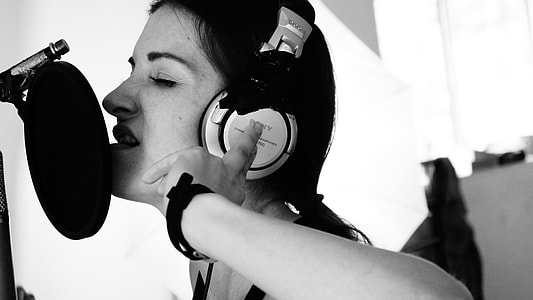 greyscale photo of woman wearing over-ear headphones near pop filter thumbnail