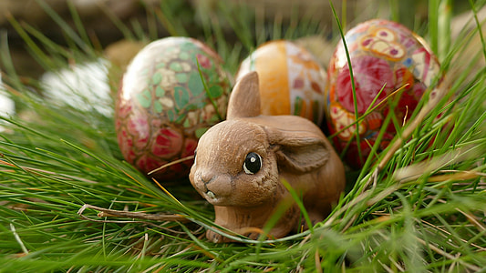 brown rabbit figurine with decorative eggs on grass thumbnail