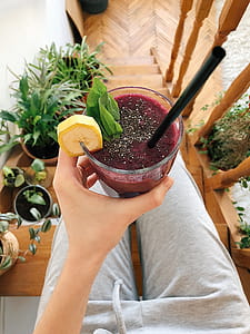 Person's Hand Holding Drinking Glass Filled With Smoothie thumbnail