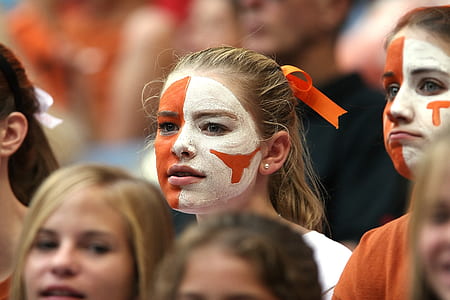 closeup photo of woman with white and orange paint on face thumbnail