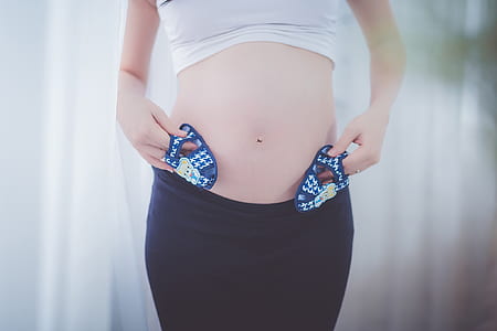 Pregnant Woman Holding Baby Shoes in Her Tummy thumbnail