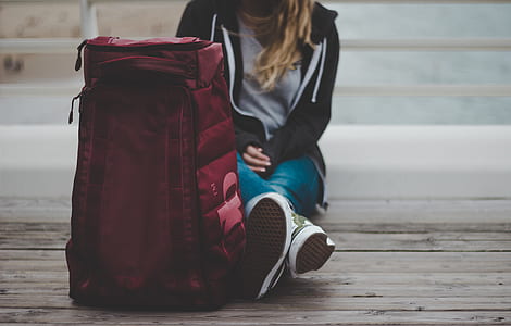 woman sitting behind red backpack thumbnail