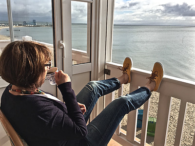 woman sitting on brown chair drinking coffee during daytime thumbnail
