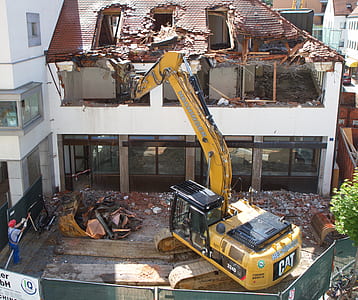 yellow Caterpillar excavator in front of white building thumbnail