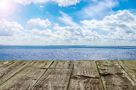 brown dock beside calm sea under white cloud blue skies thumbnail