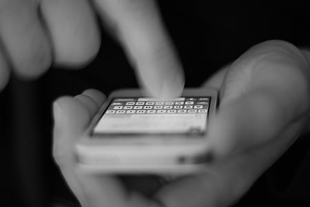 grayscale photograph of person holding white iPhone 4 thumbnail