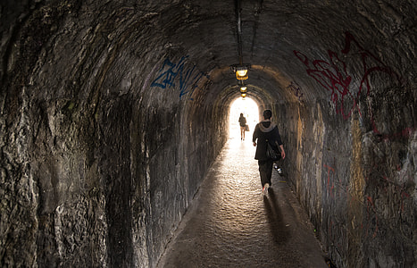 woman walking inside gray concrete tunnel thumbnail
