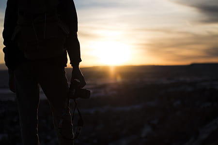 person holding camera while standing on top of the mountain during sunset thumbnail