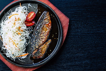 grilled fish and shredded cabbage and carrot salad dish in black plate thumbnail